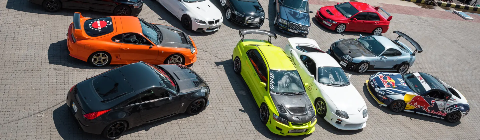 A diverse lineup of JDM sports cars, including modified and classic models, gathered for a car enthusiasts' event.