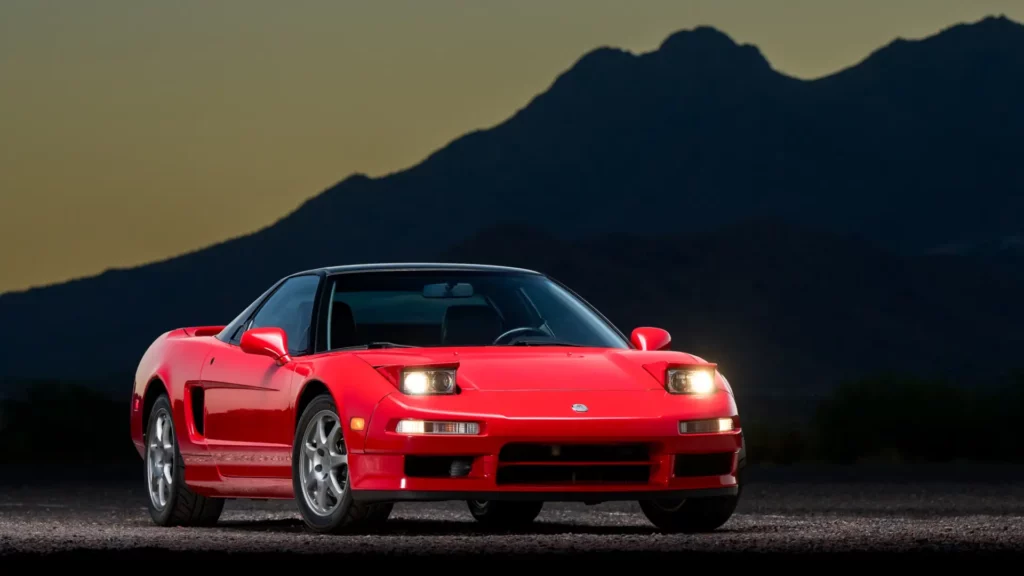 A stunning red Honda NSX, a JDM sports car icon, set against a dramatic mountain backdrop, showcasing its sleek and timeless design.