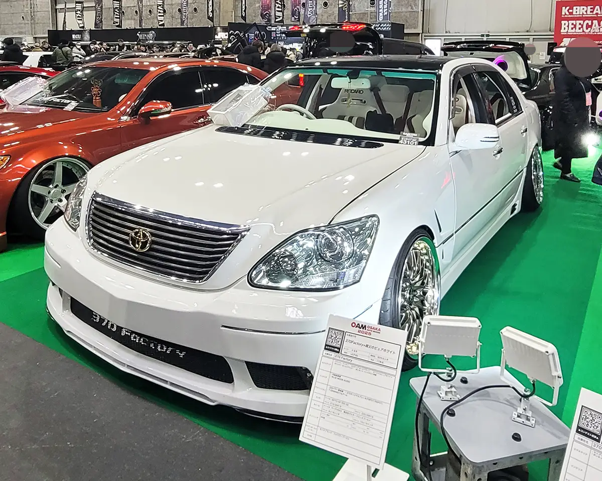 A heavily customized Toyota Celsior with chrome wheels, slammed suspension, and an elegant white finish.