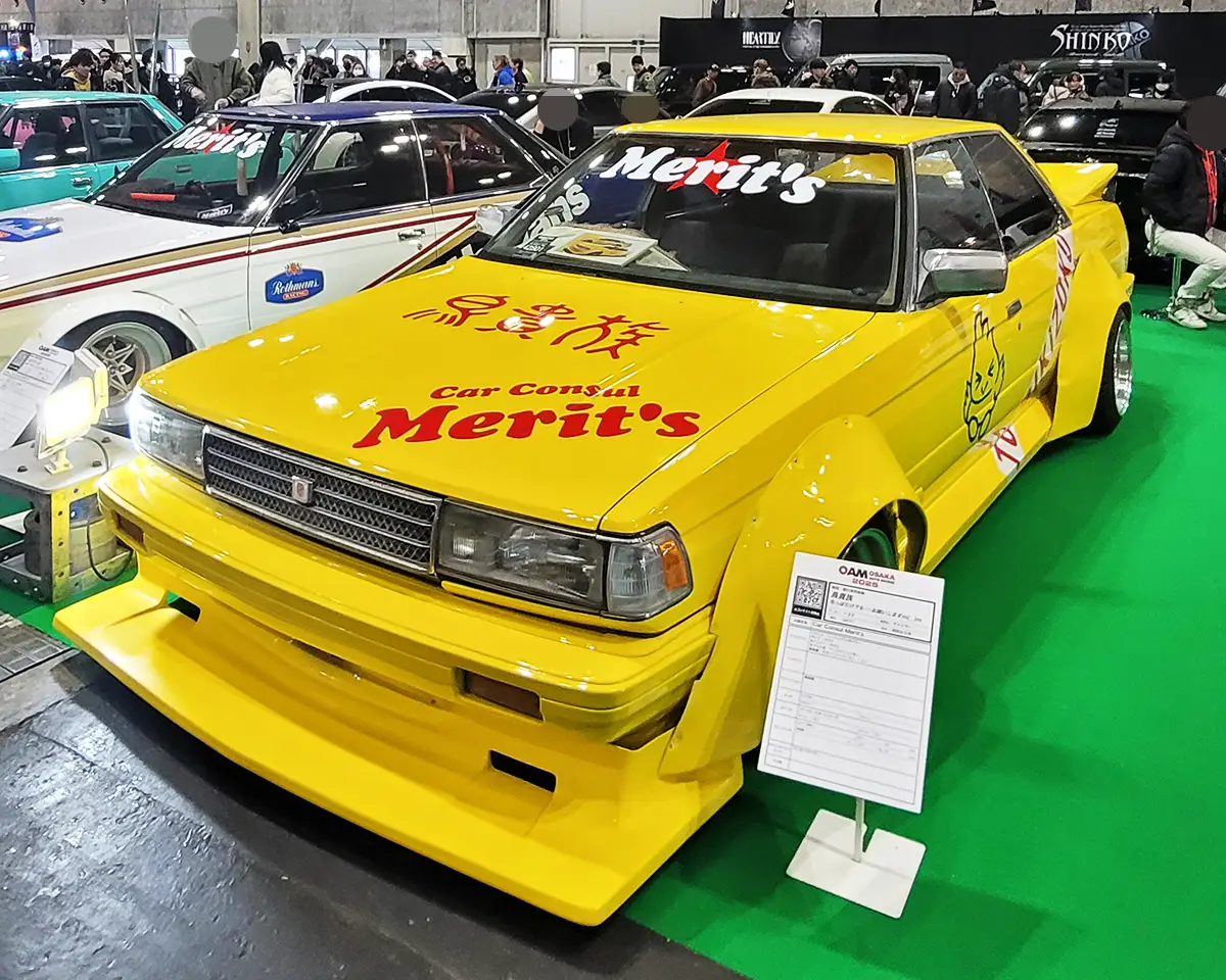 A bright yellow Toyota Mark II, customized in true Bosozoku style with a massive front splitter and wide fender flares.